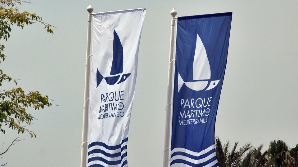 Dos banderas con el logo del Parque Marítimo del Mediterráneo
