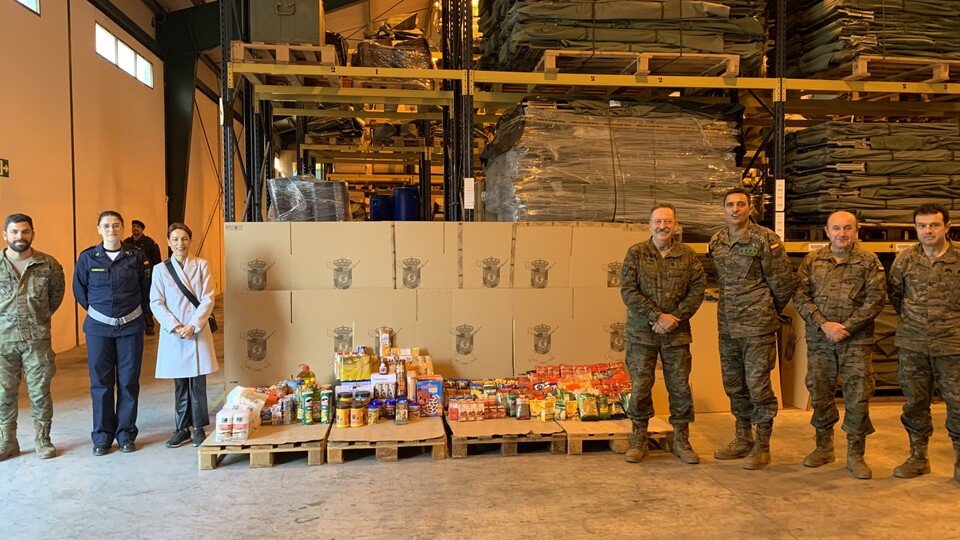 Varios militares, posando junto a unos palés de alimentos