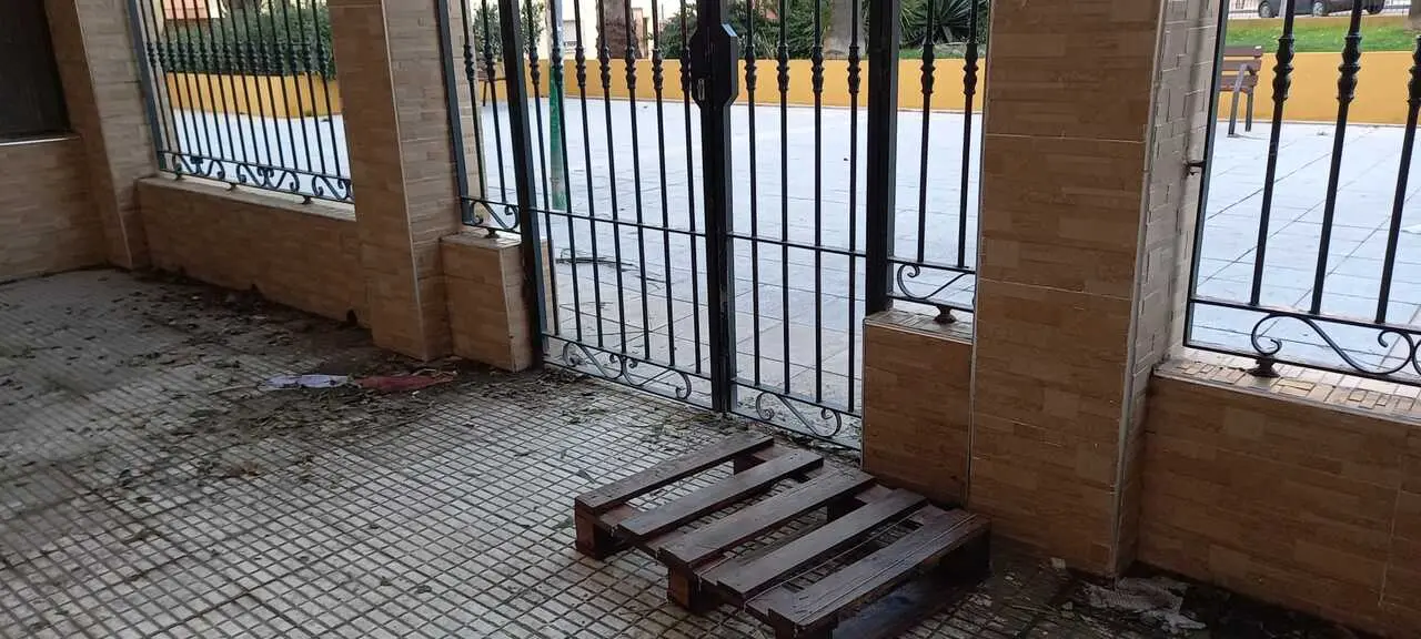 La entrada a la urbanizaci&oacute;n Loma del Pez con el palet que los vecinos utilizan para sortear las inundaciones