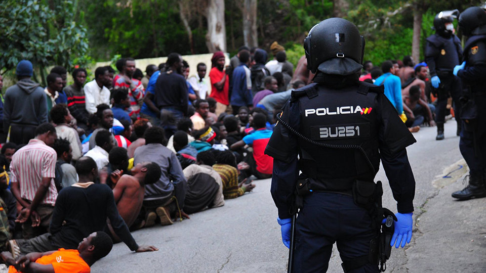 Un agente de la UIP de la Policía nacional vigila a migrantes subsaharianos recién llegados