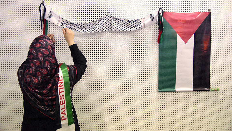 Una mujer coloca una bandera de Palestina en la sala de usos múltiples de la Biblioteca