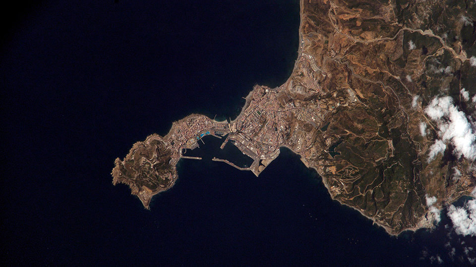 ISS015-E-18808 (21 July 2007) --- Ceuta on the northern African coastline is featured in this image photographed by an Expedition 15 crewmember on the International Space Station. The small Spanish enclave of Ceuta occupies a narrow isthmus of land on the African side of the Strait of Gibraltar. This view illustrates the sharp contrast in land cover between urban Ceuta (pink to white residential and industrial rooftops at center), the bay formed by seawalls to the north of the city, and the higher elevations of Monte Hacho forming the end of the isthmus. Green, vegetated slopes surround the Spanish fort atop the mountain, which commands a clear view of the Strait of Gibraltar to the northwest (not shown).  Several small dots are visible near the coastline to the northwest and south of Ceuta -- these are small pleasure or fishing boats.