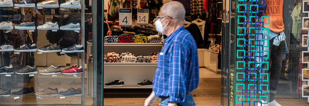 Un hombre con mascarilla pasa frente a una tiemda en el Paseo del Revellín
