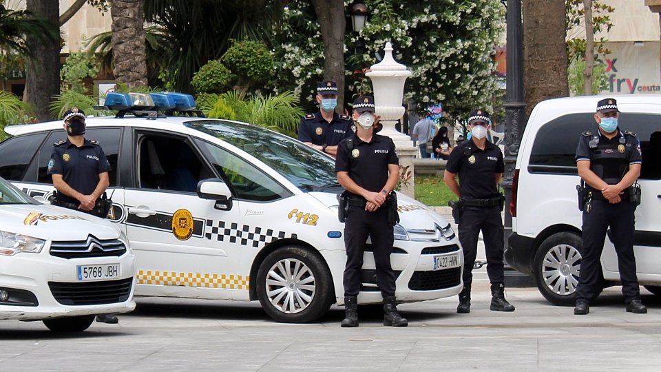 Varios policías locales, guardando un minuto de silencio frente a sus vehículos