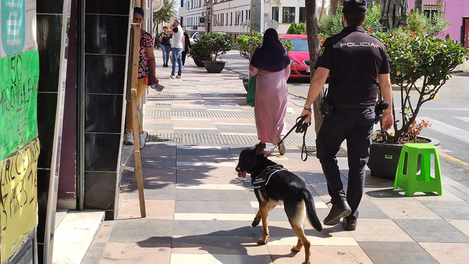 Un agente de Policía Nacional patrulla a pie con un perro por una zona comercial