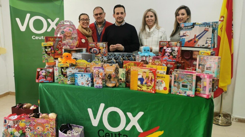 Varios miembros de VOX y Cáritas Diocesana, posando junto a multitud de juguetes