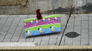 Una mujer carga con un colch&oacute;n infantil en el desalojo de Huerta T&eacute;llez