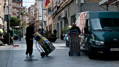 Dos trabajadores descargan una furgoneta en la Calle Camoens.-1