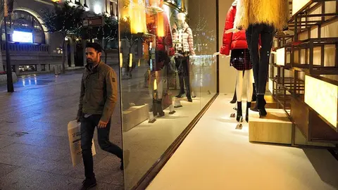 Un viandante pasa ante el escaparate de una de las grandes franquicias del Paseo del Revell&iacute;n