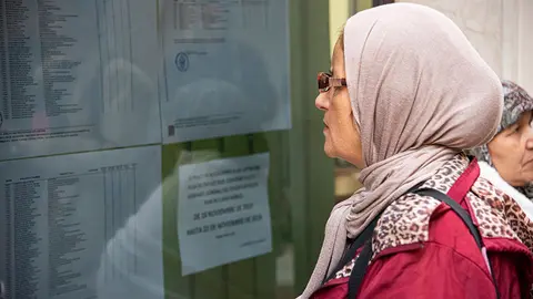 Una mujer, consultando un listado del Plan de Empleo