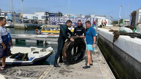 Varios buzos, tras sacar un neum&aacute;tico del mar