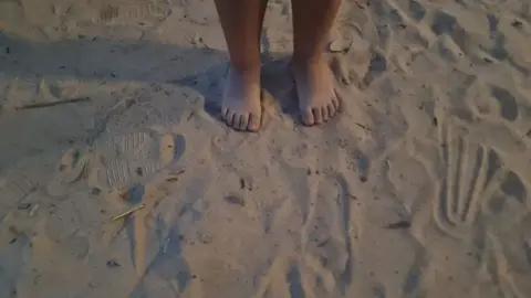 Los pies de un ni&ntilde;o en un parque infantil con arena