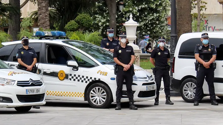 Varios polic&iacute;as locales, guardando un minuto de silencio frente a sus veh&iacute;culos