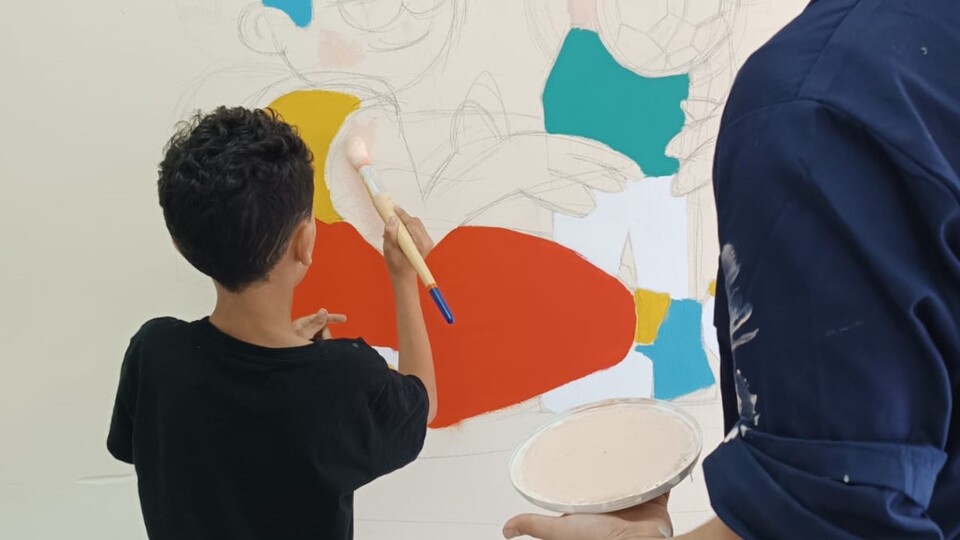 Un niño, pintando el nuevo mural del local social de Príncipe Alfonso