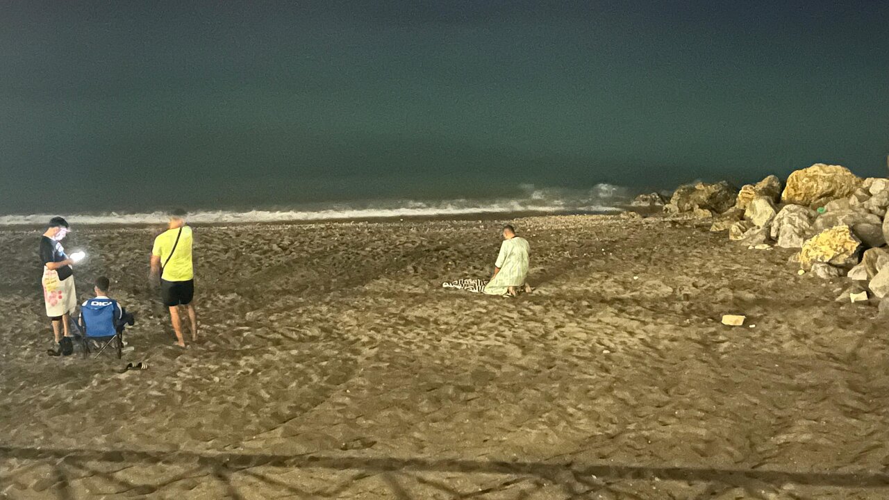Un hombre rezando en la playa del Tarajal.